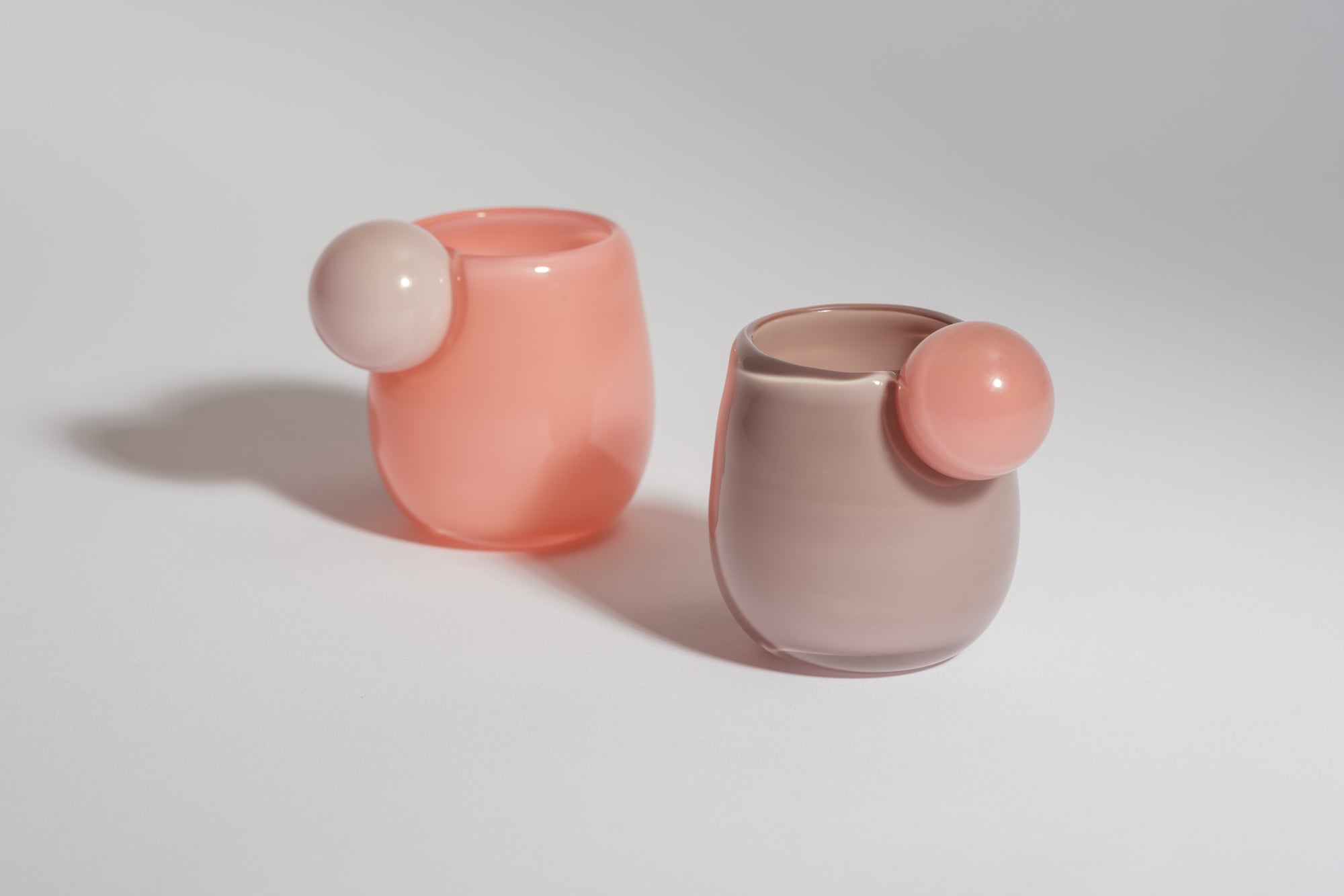 two small cups with a ball on the side in purple, pink and white